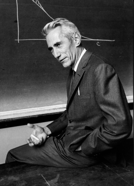 Photo of Claude Shannon sitting in front of blackboard